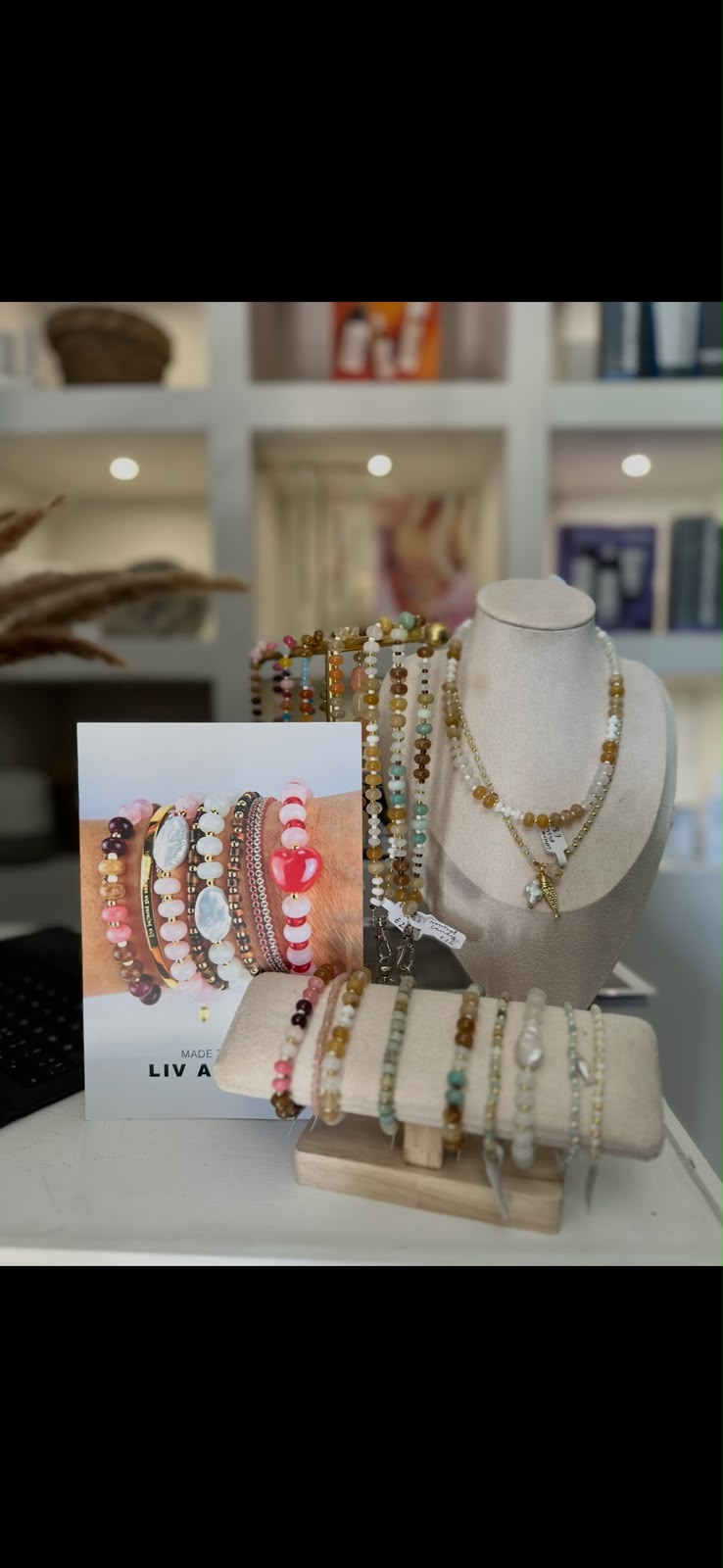 Beaded gemstone necklaces and bracelets displayed on a cream stand in the studio