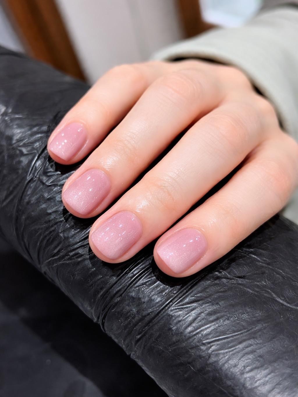 A soft pink shimmer gel manicure on short natural nails