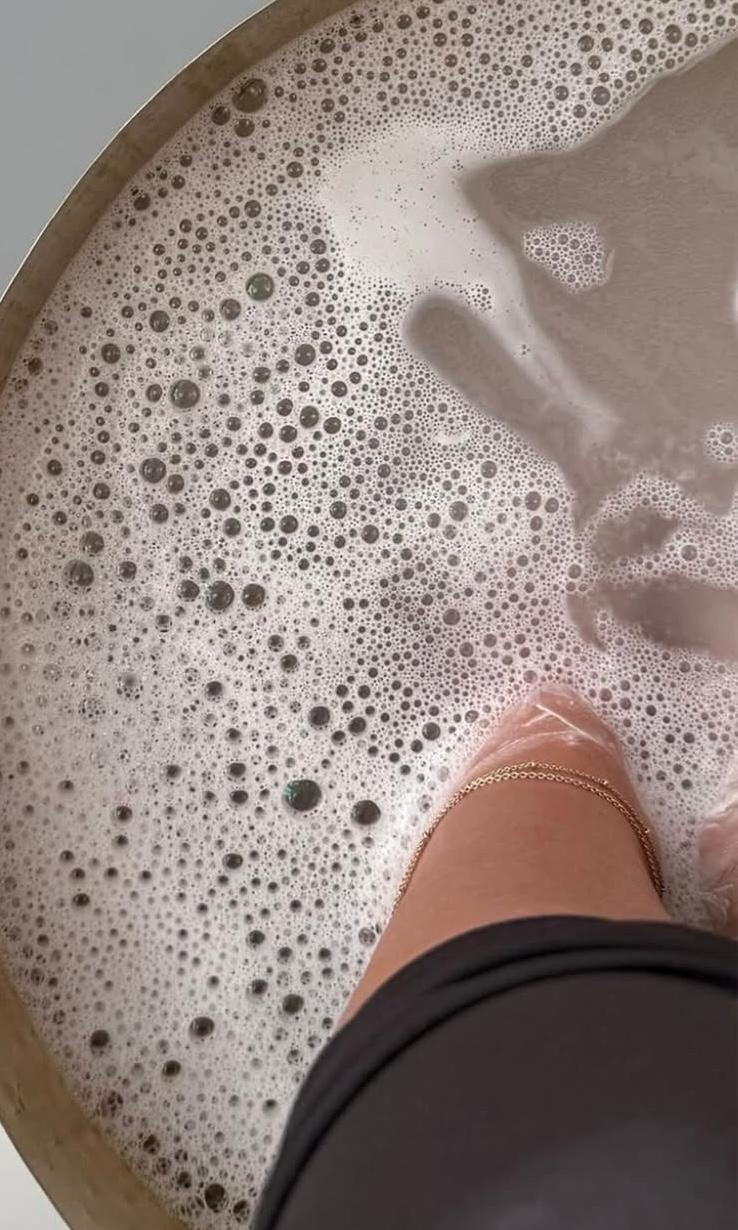Feet resting in a warm, foaming pedicure bowl