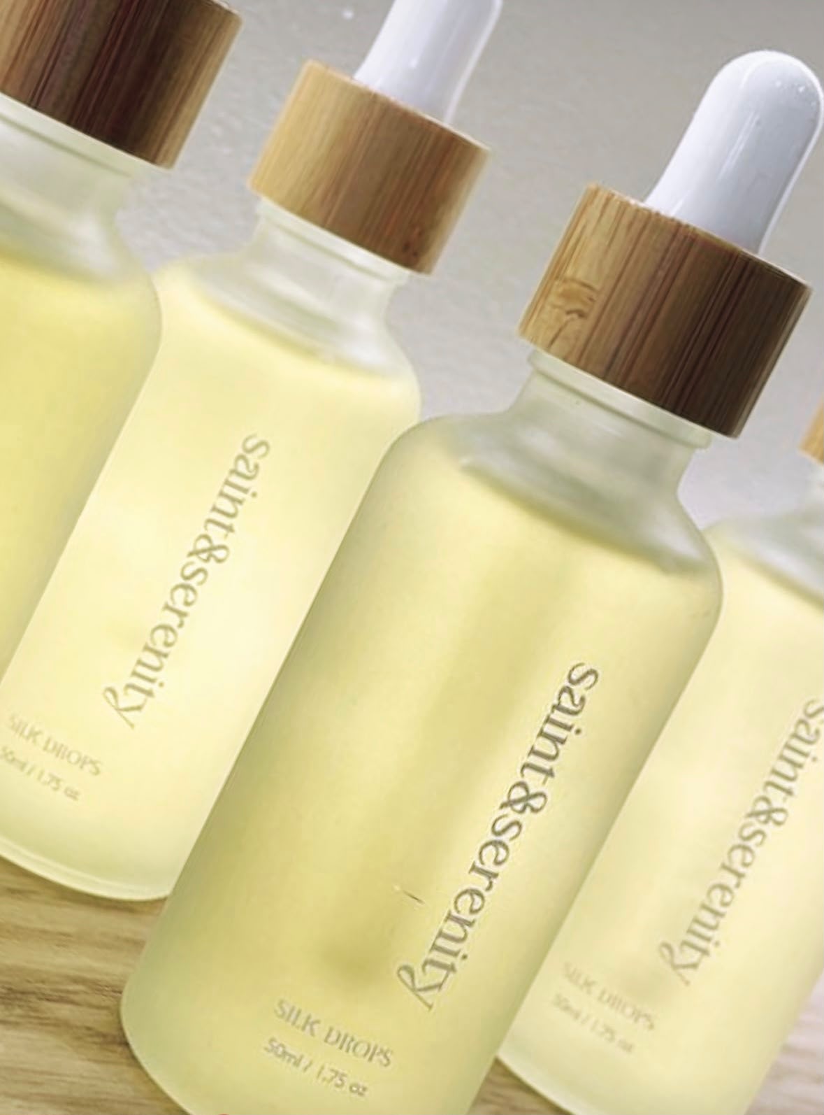 Saint and Serenity Silk Drops serum bottles on a wooden surface at the studio